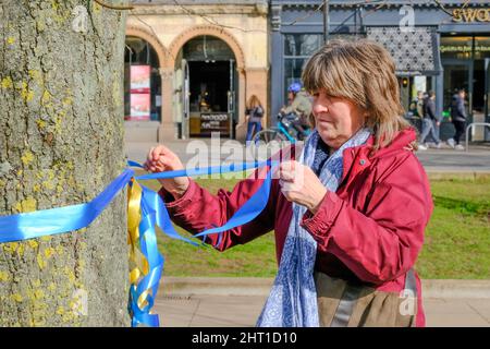 Ristol, Regno Unito. 26th Feb 2022. Teddy Braden di Bristol lega nastri gialli e blu, il colore della bandiera Ucraina, ad un tree.People si riuniscono sul College Green di Bristol per mostrare il loro sostegno per la popolazione Ucraina dopo l'invasione da parte della Russia. Credit: JMF News/Alamy Live News Foto Stock