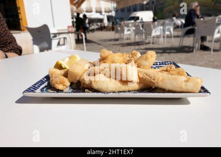 Strisce di seppie fritte, chiamate Chocos Fritos in spagnolo. Servito su un piatto rettangolare decorativo. Cucina spagnola. Foto Stock