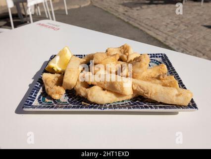 Strisce di seppie fritte, chiamate Chocos Fritos in spagnolo. Servito su un piatto rettangolare decorativo. Cucina spagnola. Foto Stock