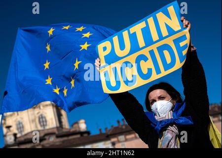 Torino, Italia. 26 febbraio 2022. Un dimostratore ha un cartello con la scritta "Putin uccide” mentre una bandiera dell'Unione europea si sta tessendo durante una protesta contro l'operazione militare russa in Ucraina. Il 24 febbraio 2022, la Russia ha lanciato un'invasione su larga scala dell'Ucraina. Credit: Nicolò campo/Alamy Live News Foto Stock