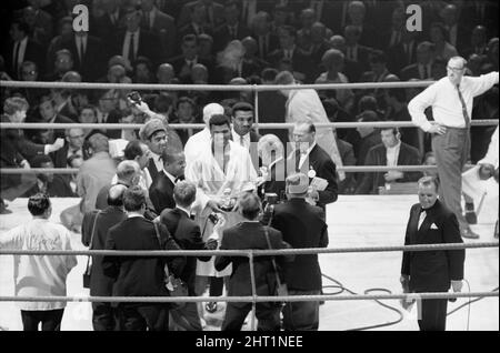 Il 6 agosto 1966 presso la Earls Court Arena di Kensington, Londra, Inghilterra, il campione di pesi massimi Muhammad Ali di Louisville, Kentucky, difese il suo titolo contro Brian London, di Blackpool, Inghilterra. Ali è stato inbattuto a 24-0 in arrivo. Londra era 35-13. La lotta era prevista per 15 turni. Quando gli fu chiesto se voleva un rimatch con Ali, Londra disse: “Solo se lega un peso di 56 libbre a ciascuna gamba…” Ali ha battuto Londra nel terzo turno. (Foto) Ali (al centro) sorridendo dopo la sua terza vittoria al round. Foto Stock