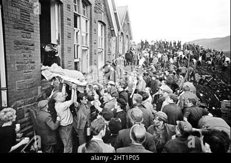 Aberfan, Galles del Sud, 21st ottobre 1966 il disastro di Aberfan è stato un crollo catastrofico di una punta di petrolio collirica nel villaggio gallese di Aberfan, vicino a Merthyr Tydfil. È stato causato da un accumulo di acqua nella roccia accumulata e scisto, che improvvisamente ha iniziato a scivolare in discesa sotto forma di slurry e ha inghiottito la scuola junior Pantglas sottostante, il 21st ottobre 1966, uccidendo 116 bambini e 28 adulti. La foto mostra un corpo che è stato scoperto, è passare dalla finestra della scuola per la gente del posto e servizi di salvataggio aiutare Foto scattata 21st ottobre 1966The eventi di Venerdì, 21 ottobre 1966 T Foto Stock