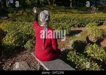 donna matura irriconoscibile in un giardino del tè Foto Stock