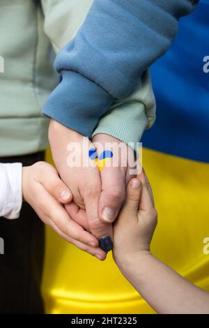 Mani di bambini e adulti insieme, un cuore disegnato nei colori giallo e blu della bandiera Ucraina. Famiglia, unità, sostegno,. L'invasione russa di Ukra Foto Stock