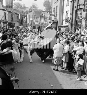 I visitatori e gli esuli di città e Cornovaglia che ritornano ogni anno prendono parte alle celebrazioni di 36 ore al Padstow 'Obby 'Oss festeggiamenti per araldo nel mese di maggio con gli antichi diritti di primavera. Nella foto, il cavallo hobby cavorting tra la folla di vacanze in Padstow Street. 2nd maggio 1966. Foto Stock