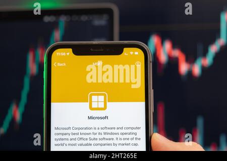 Il prezzo delle azioni di Microsoft aumenta sul mercato commerciale con grafico a barre a linee di tendenza sullo sfondo. Uomo con un telefono cellulare con logo aziendale, febbraio 2022, San Francisco, USA Foto Stock