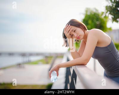 asian giovane forte, donna fiduciosa in abiti sportivi sensazione di male in procinto di buttare in su. Disidratazione. Dolore toracico. Cucitura laterale, crampi laterali dopo il funzionamento. Mal di stomaco dopo il jogging. Foto Stock