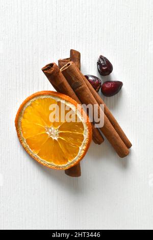 Cannella, arancio secco e fianchi di rosa su sfondo bianco. Foto Stock