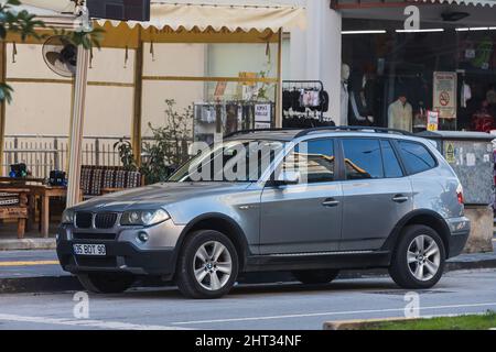 Side; Turchia – Febbraio 06 2022 : la BMW grigia X3 è parcheggiata in strada in una calda giornata autunnale sullo sfondo di un edificio, recinzione Foto Stock