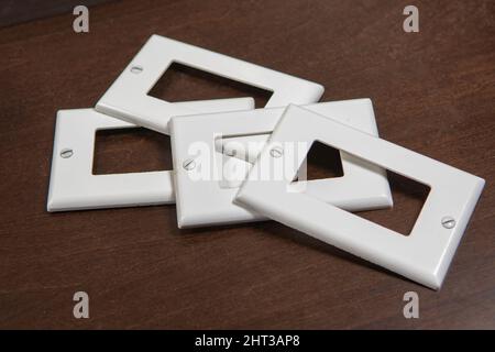Due interruttori, una presa e tre coperchi in plastica decorativi bianchi separati per una presa o un interruttore Foto Stock