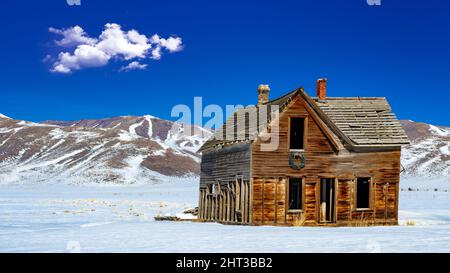 Casa in legno intemperiato con una corona sopra la porta in inverno Foto Stock