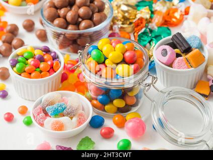 Caramelle al cioccolato al latte in guscio con gomme da zucchero gelate e liquirizia e caramelle di sherbet di frutta su sfondo bianco. Con marshmallow e stra Foto Stock