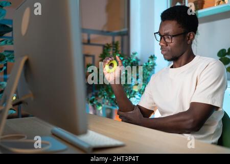 Nero ragazzo maschio freelancer esercitarsi con anello di presa in silicone o espansore della mano a casa accogliente ufficio Foto Stock