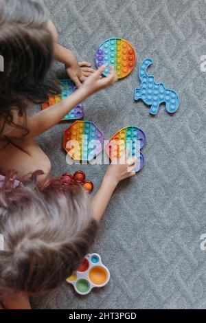 Vista dall'alto ai bambini che giocano con i giocattoli pop it Foto Stock