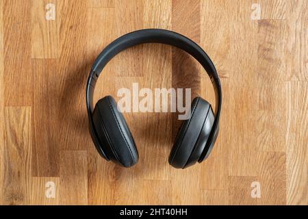 Vista dall'alto delle cuffie wireless nere su sfondo di legno Foto Stock