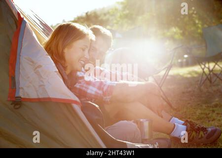 Vanno sempre in campeggio. Una giovane coppia seduta all'ingresso della loro tenda. Foto Stock