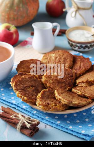 Pancake fatti in casa con zucca e mele per la prima colazione, così come una tazza di caffè con latte su sfondo azzurro chiaro, formato verticale Foto Stock