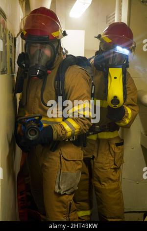 MAR DELLE FILIPPINE (Feb 1, 2022) Hull Maintenance Technician 3rd Class Thomas Waddell, a sinistra, nativo di Oakdale, California, opera un tubo antincendio come Damage Controlman 3rd Class Evan Roberts, a destra, da Henry County, GA., opera una termocamera durante un'esercitazione per il controllo dei danni a bordo di una nave di atterraggio anfibio Harpers Ferry USS Pearl Harbor (LSD 52), nel Mare delle Filippine, 1 febbraio 2022. Marine Exercise Philippines (MAREX PH) dimostra l'impegno degli Stati Uniti nei confronti della regione e dei nostri alleati di lunga data. Cerchiamo di costruire relazioni durature e reciprocamente vantaggiose e investiamo nella formazione per e Foto Stock