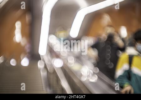 Luci bokeh luminose nell'immagine sfocata delle persone sulla scala mobile sotterranea Foto Stock