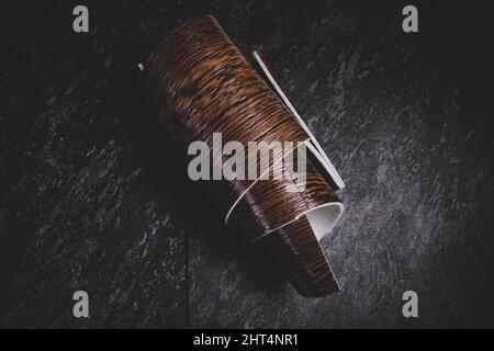 Linoleum. Rotolo di linoleum su sfondo nero. Rivestimenti per pavimenti. Posa di rivestimenti per pavimenti. Tessitura di legno su un rotolo. Il campione viene arrotolato. Foto Stock