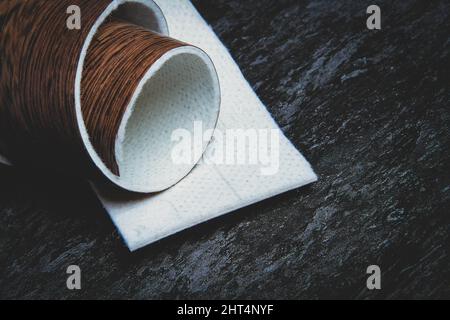 Linoleum. Rotolo di linoleum su sfondo nero. Rivestimenti per pavimenti. Posa di rivestimenti per pavimenti. Tessitura di legno su un rotolo. Il campione viene arrotolato. Foto Stock