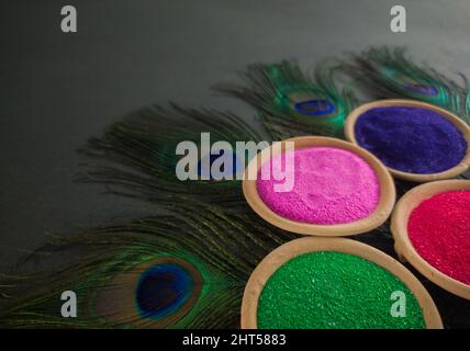 polveri colorate per holi su pentole di argilla in occasione del festival indiano dei colori. holi tema felice girato su sfondo nero con piume di pavone. Foto Stock