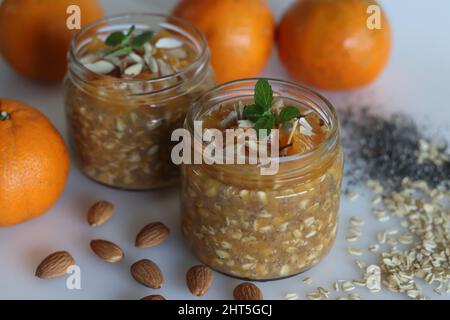 Avena e semi di chia refrigerati per una notte in succo d'arancia, serviti con mandorle tritate e miele. Scatto su sfondo bianco. Una colazione facile e sana. Foto Stock