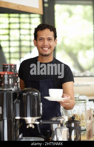 Fantasia una tazza fresca di joe. Shot di un bel barista che serve una tazza di caffè fresco. Foto Stock