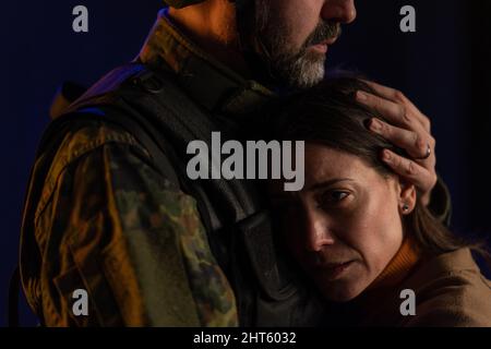Primo piano di donna triste piangendo quando abbraccia il suo marito militare e salutandolo. Foto Stock