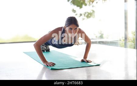 Lavorando sulla sua parte superiore del corpo. Scatto di una giovane donna attraente che si sta allenando in uno studio con una vista. Foto Stock