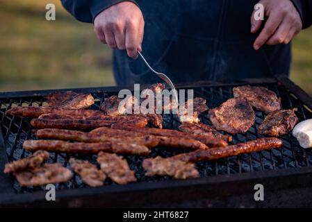 Primo piano di carne e salsicce grigliate in un parco Foto Stock