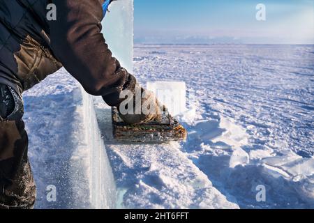 Lo scultore lucida il ghiaccio con un attrezzo fatto a mano per fare le sculture di ghiaccio sul lago Baikal. Foto Stock