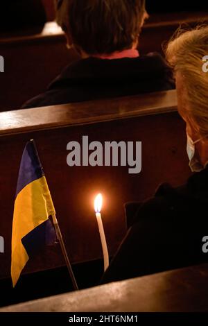 Una donna detiene una bandiera Ucraina e una candela che brucia durante la veglia. Una veglia congiunta per il popolo ucraino si è svolta nella Chiesa di Senhora da Conceição in Piazza Marquês, a Porto, organizzata dalla Parrocchia Ortodossa Ucraina di San Pantaleon e dalla Parrocchia Cattolica di Senhora da Conceição. Foto Stock