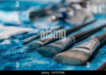 Primo piano dei pennelli dell'artista in diverse dimensioni e forme sulla superficie bianca Foto Stock