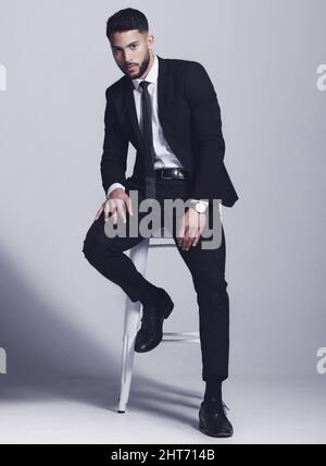 Indossando il mio abito migliore. Studio girato di un giovane che si posa su uno sfondo grigio. Foto Stock
