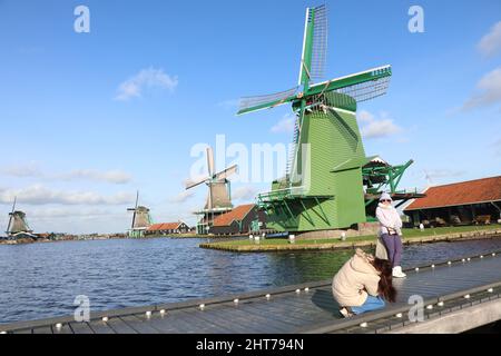 Turisti che scattano fotografie di fronte a mulini a vento Zaanse Schans, Zaandam, Paesi Bassi, gennaio 2022 Foto Stock