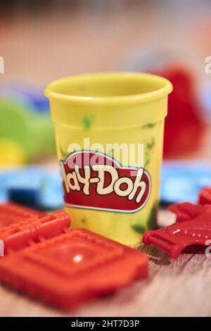Colpo verticale di una vasca OH Play-Doh con giocattoli di plastica accanto ad esso su uno sfondo sfocato Foto Stock
