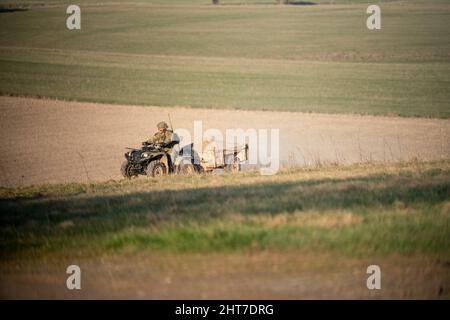 Soldato dell'esercito britannico che guida un quad e un rimorchio per tutti i terreni lungo una pista di pietra polverosa Foto Stock