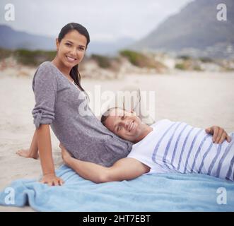 Io e il mio bambino sulla spiaggia. Scatto di un bel giovane uomo sdraiato sul suo giro di fidanzate alla spiaggia. Foto Stock