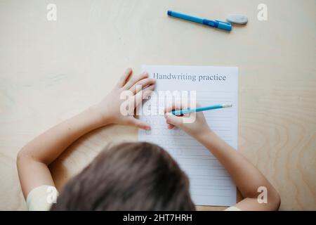 Uno scolaro che fa una lezione di matematica seduto alla scrivania nella stanza dei bambini Foto Stock