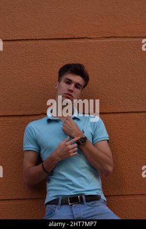 Colpo verticale di un giovane maschio attraente che si posa puntando al suo orologio Foto Stock
