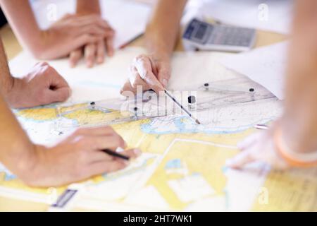 Individuare il bersaglio è il passo uno. Scatto ritagliato di un gruppo di bagnini maschi irriconoscibili che trovano coordinate su una mappa nel loro ufficio. Foto Stock