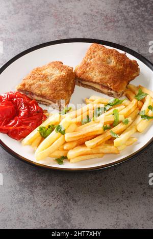 Bistecca spagnola impanato Cachopo servito con patatine fritte da vicino in un piatto sul tavolo. Verticale Foto Stock