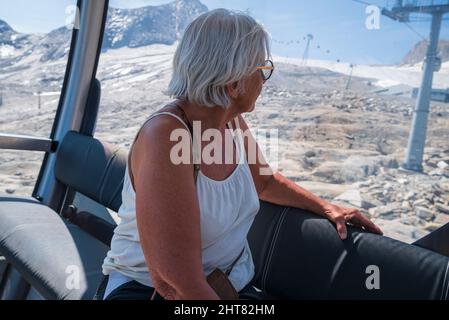 Donne anziane che guardano fuori da dentro una cablecar nelle alpi, foto dalla zona di kitzsteinhorn Austria. Messa a fuoco in primo piano. Foto Stock