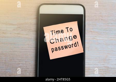 È ora di cambiare il testo della password su blocco note con smartphone su scrivania in legno. Foto Stock