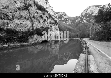 Foto in scala di grigi di un fiume e di una strada tra il canyon di Gola del Furlo in provincia di Pesaro Foto Stock