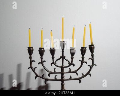 Primo piano di un candelabro a sette ramificazioni con candele su sfondo bianco per Hanukkah Foto Stock