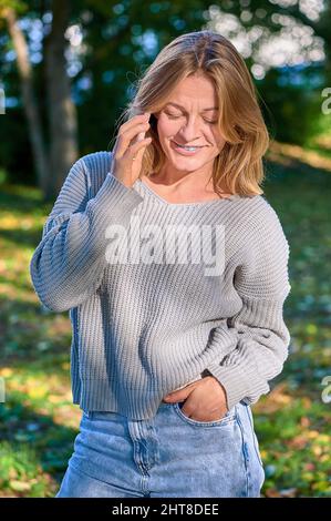 Bella donna che parla al telefono nel parco in estate Foto Stock