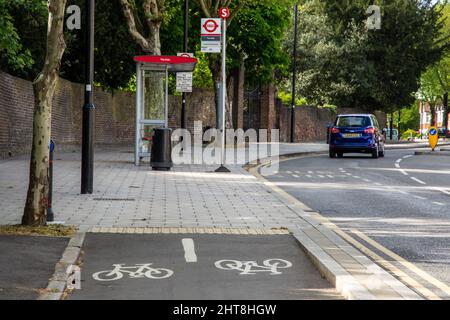 Una pista protetta passa a un marciapiede per uso condiviso per ospitare una fermata dell'autobus nella periferia ovest di Londra. Foto Stock