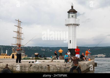 Varna, Bulgaria - 16 luglio 2014: I pescatori sono vicino alla torre bianca del faro nel porto di Varna Foto Stock